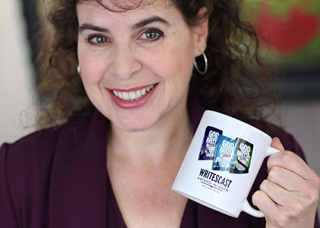 Silvia Acevedo holding a mug showing the covers of her books, the God Awful series, with the words "Award Winner 2019 Most Listens" for The Writescast Network podcast.