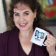 Silvia Acevedo holding a mug showing the covers of her books, the God Awful series, with the words "Award Winner 2019 Most Listens" for The Writescast Network podcast.