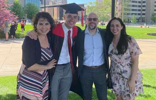 Photo shows a college graduate in cap and gown with his proud parents