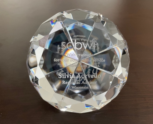 Silvia Acevedo receives an outstanding service award - a glass diamond paperweight - from the Society of Children's Book Writer and Illustrators