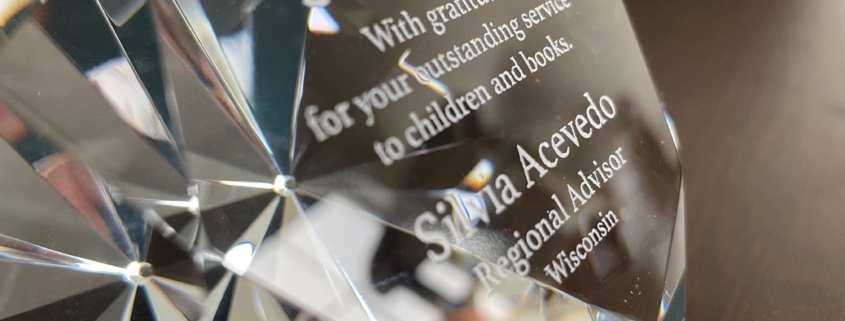 Silvia Acevedo receives an outstanding service award - a glass diamond paperweight - from the Society of Children's Book Writer and Illustrators