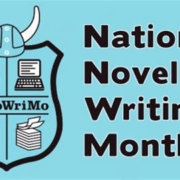 Logo for NaNoWriMo, showing an aqua blue with a shield showing writing utensils, topped with Viking horns, beside the words "National Novel Writing Month"