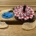 Image shows two spinning tops, a flat blue spinner and a white, black, and white spinner on a table with some maple helicopter seeds.